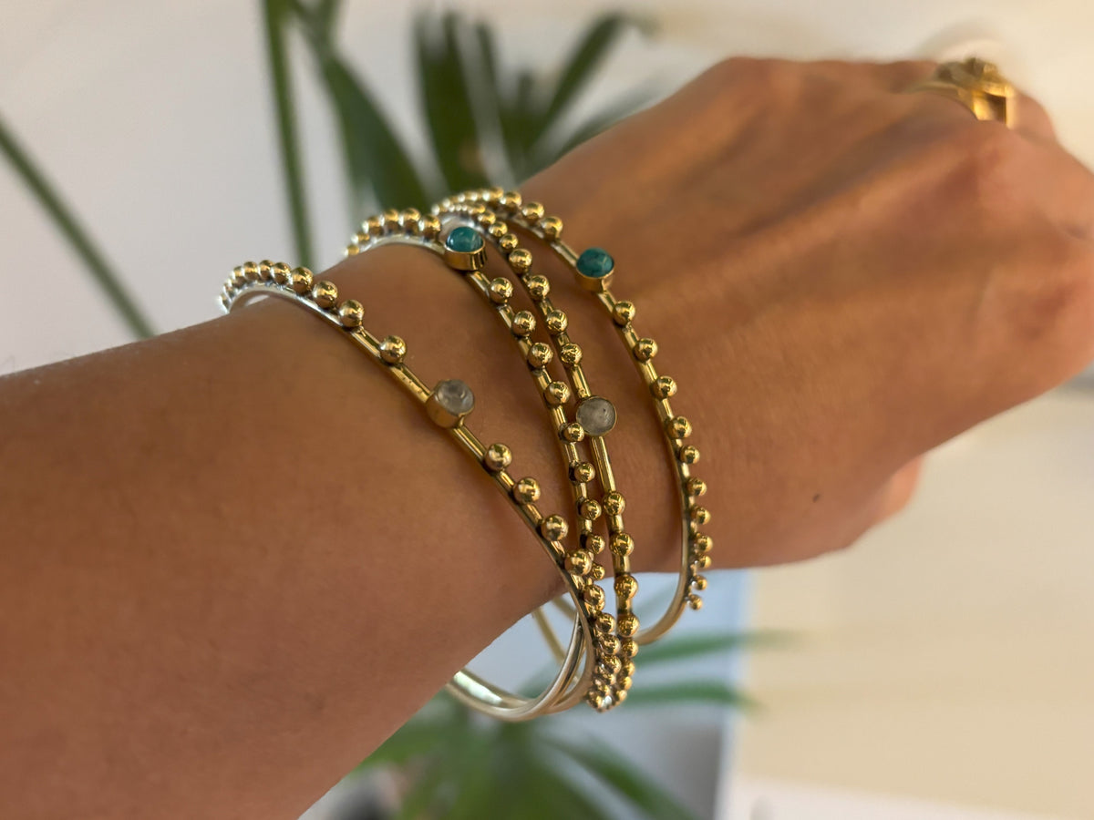 Beaded brass bangles stacked on a wrist