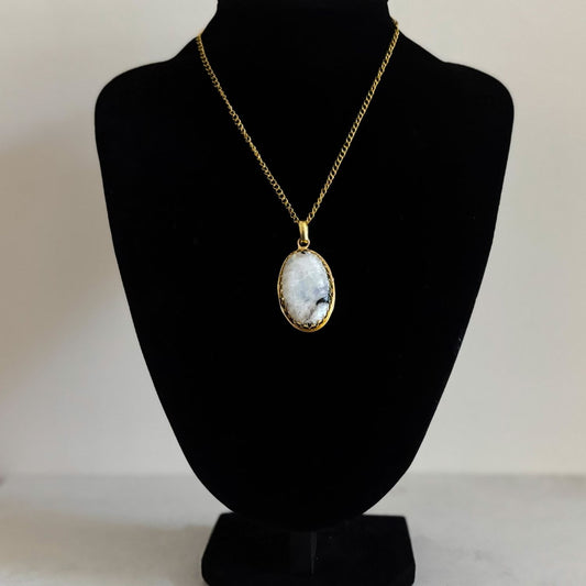 Rainbow moonstone pendant necklace on a gold curb chain, displayed on a black velvet bust for drape and scale