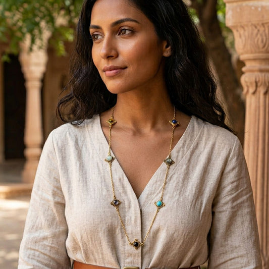 Close-up of seven stone charms on brass station necklace worn against fabric
