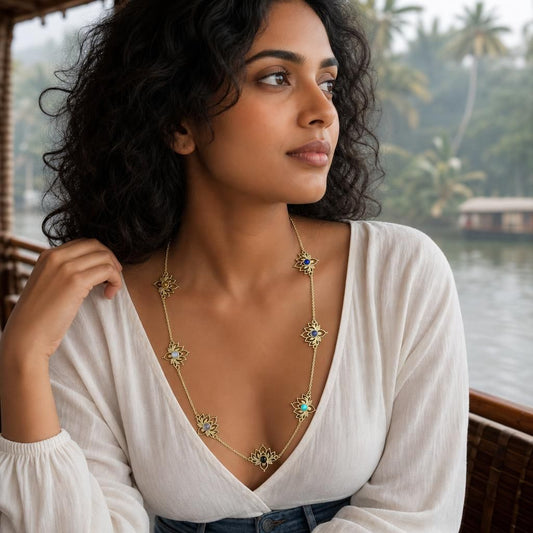 Close-up of seven lotus stone charms on brass station necklace worn against white fabric