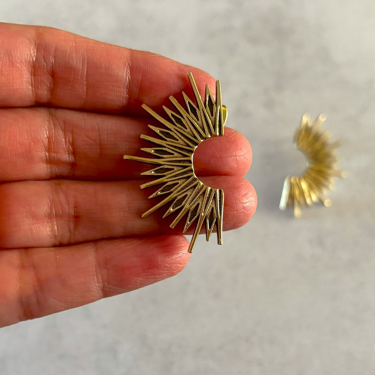 Brass Sunburst Stud Earrings — Solar Flare in golden brass, held in hand showing size