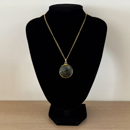 Round labradorite pendant necklace on a bust, grey-green stone on a gold curb chain