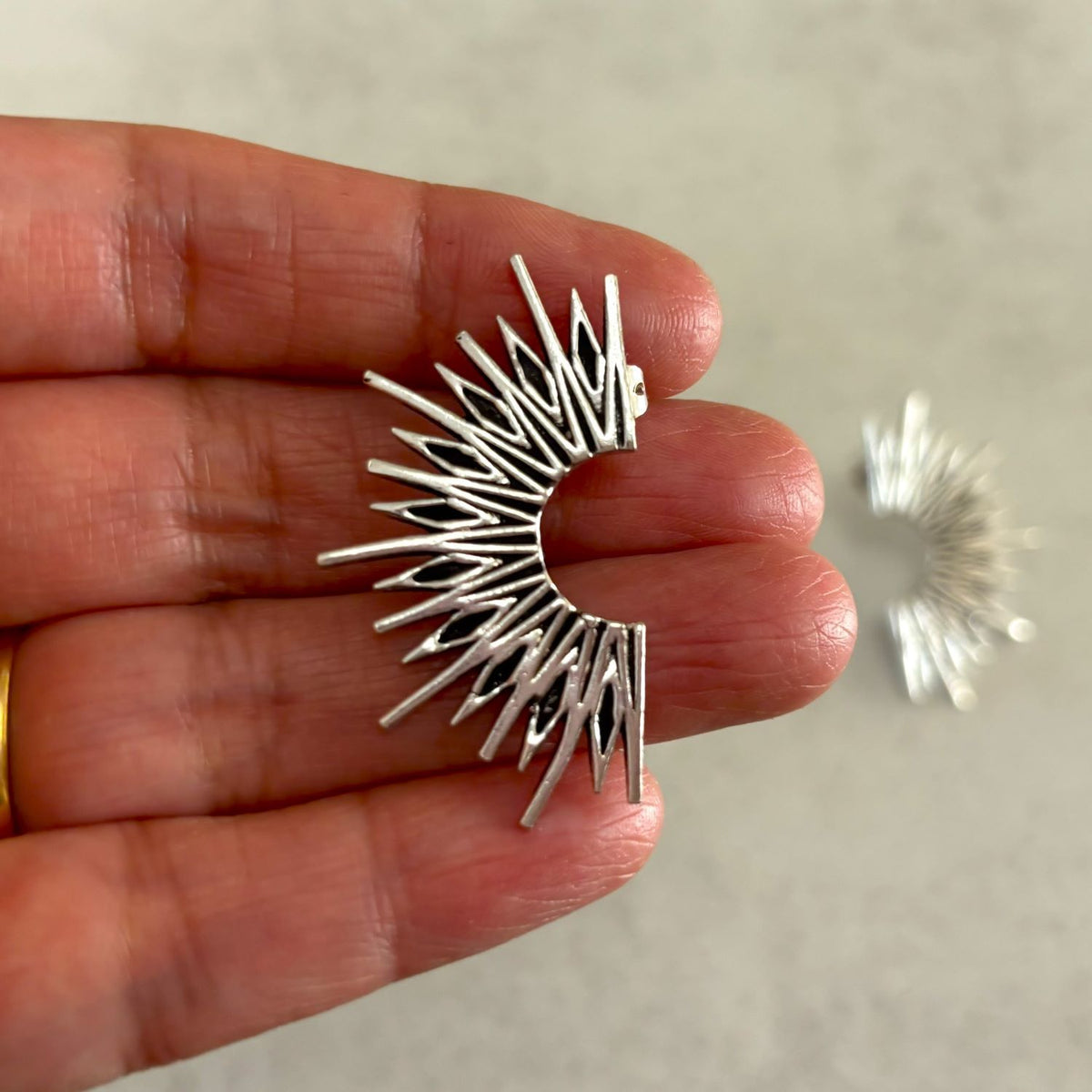 Brass Sunburst Stud Earrings — Solar Flare in silver plate, held in hand showing size