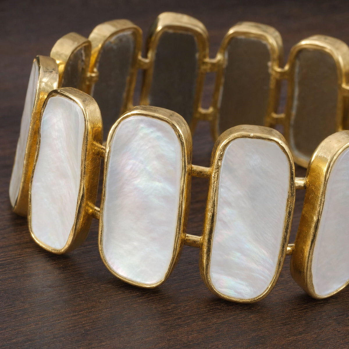 Close-up of hand-set mother of pearl slabs and organic gold bezels on the Moonshell cuff bangle