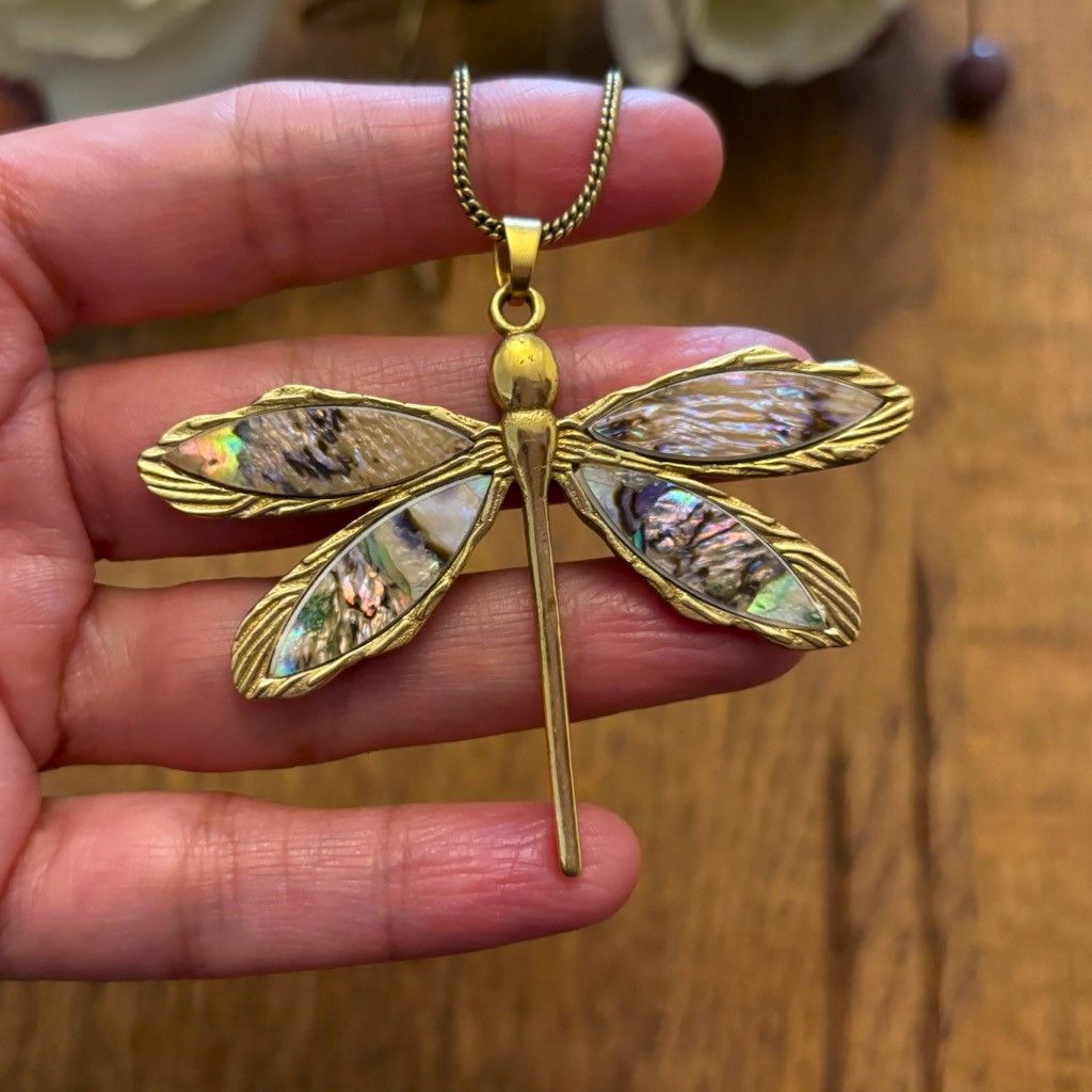 Close-up of iridescent abalone shell wings on Abalone Shell Dragonfly Pendant Necklace, held in hand for scale